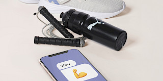 Puma x Intersport Chatbot Interface auf einem Handy neben einigem Sportequipment