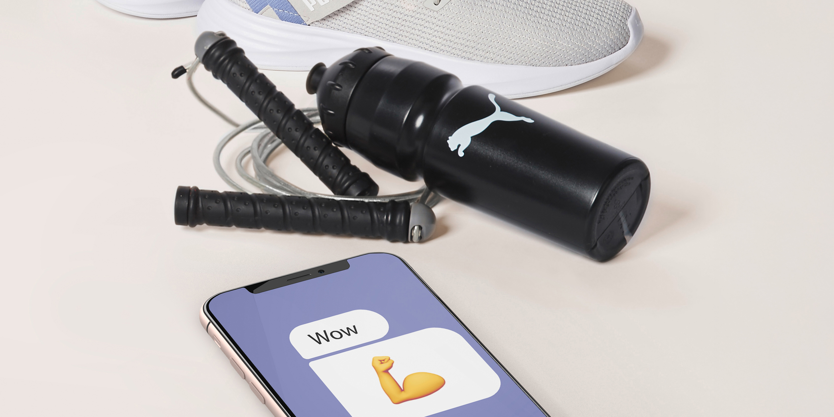 Puma x Intersport Chatbot Interface auf einem Handy neben einigem Sportequipment